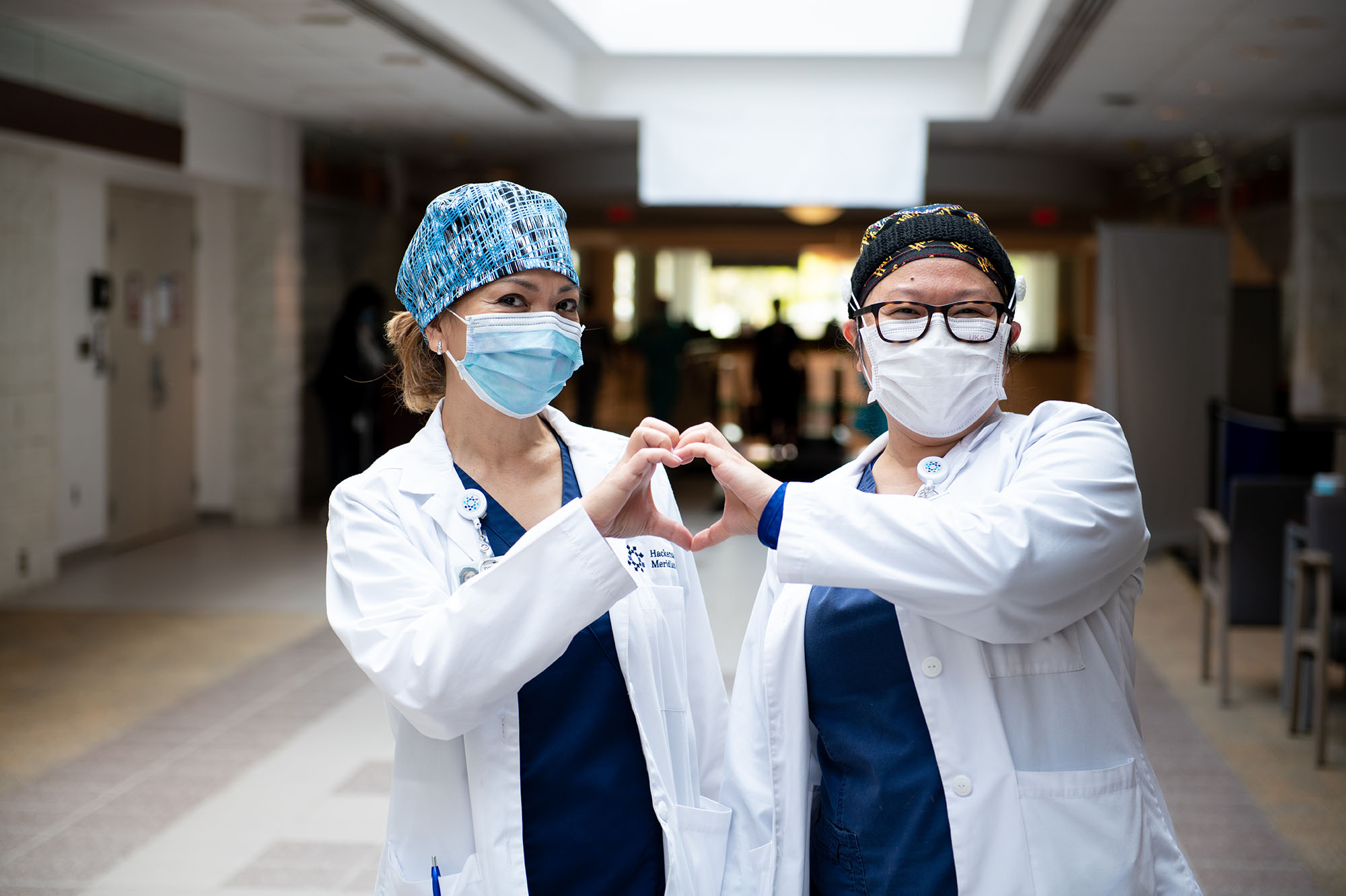 Two medical professionals positioning their hands into a heart 